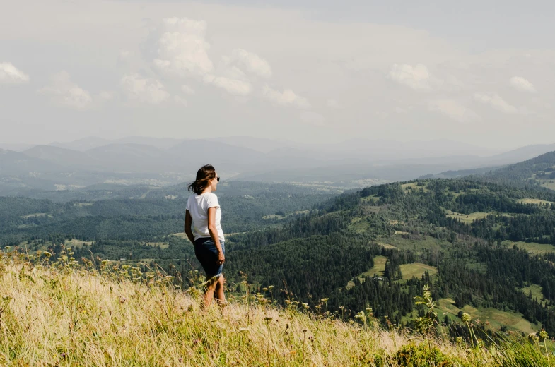 a person with sunglasses standing on a hill in the distance