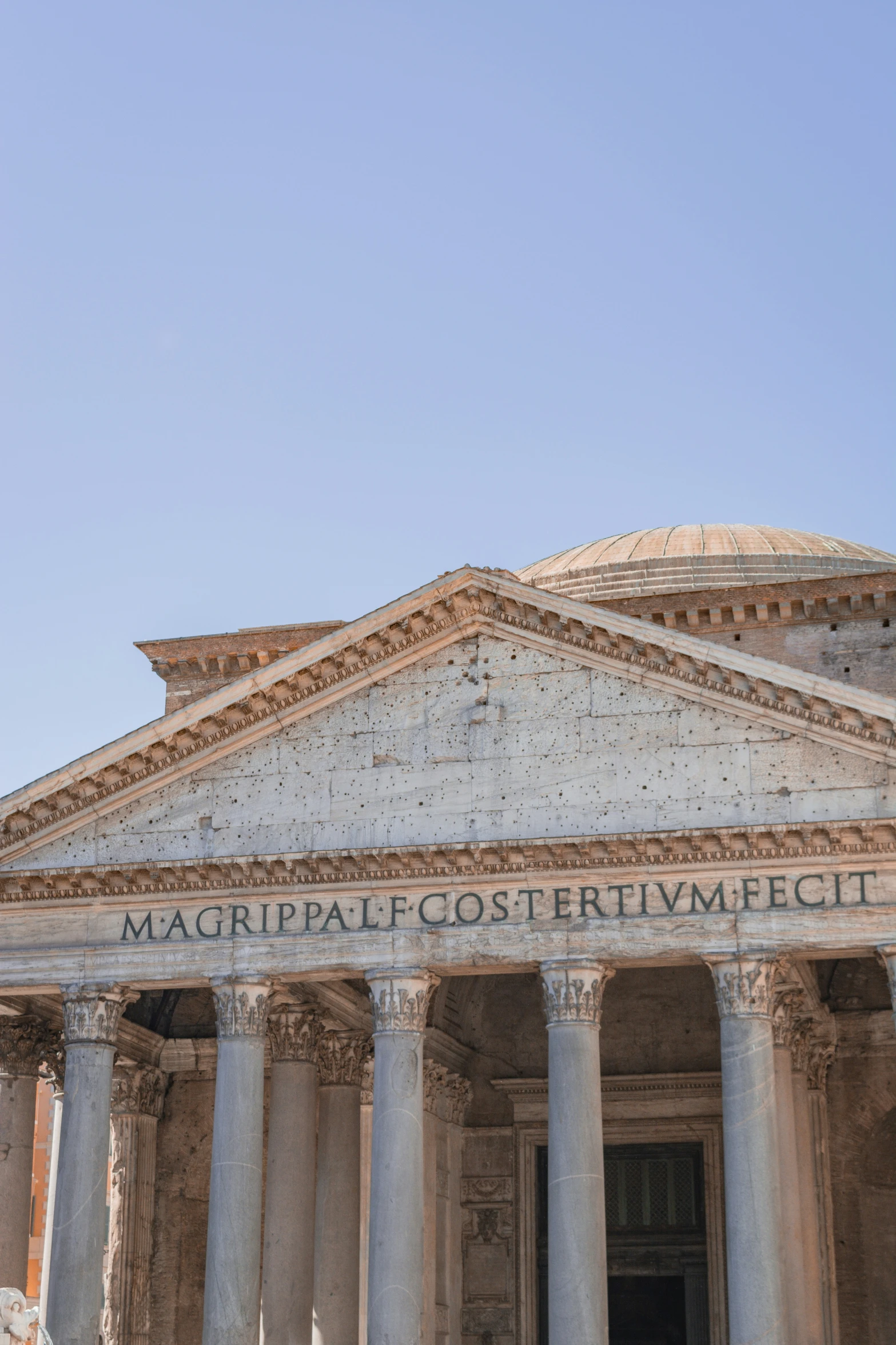 a large stone building with four pillars and a clock on the side