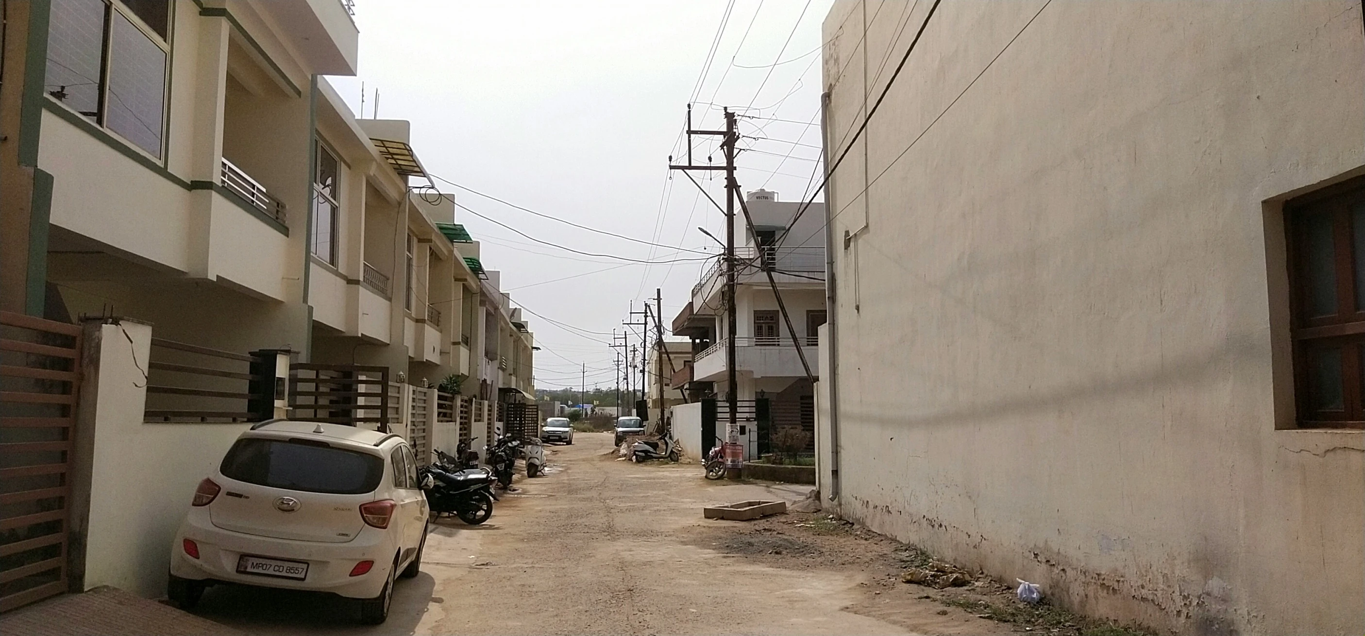 an alleyway with parked cars and motorcycles on the side