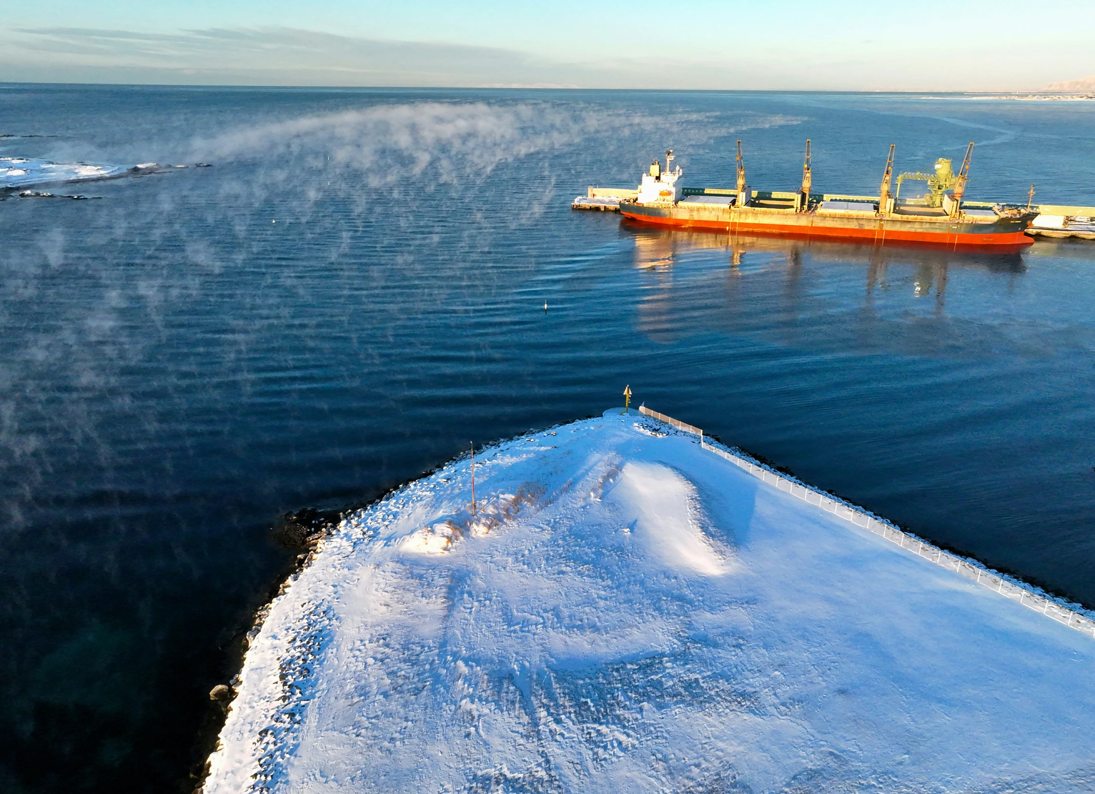 a large ice covered ship sitting near a small boat