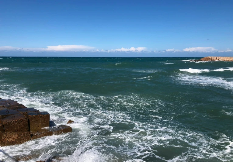 waves crashing against a sea wall on a sunny day