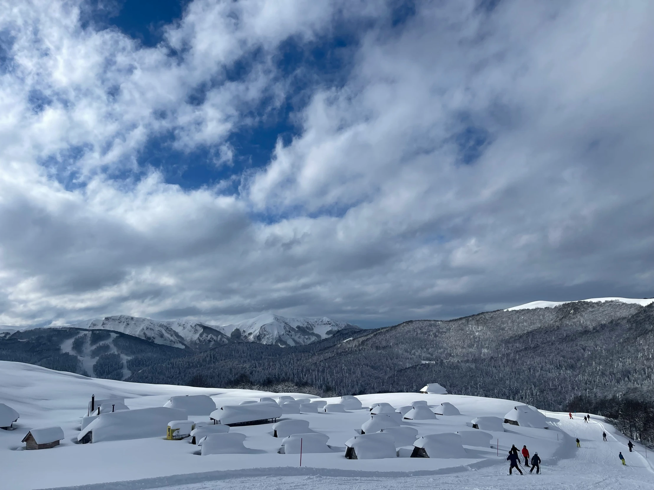 people walking up a snow covered hill to ski