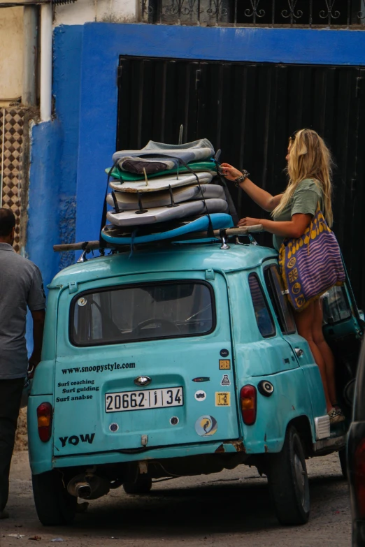 a woman loads luggage on top of a car