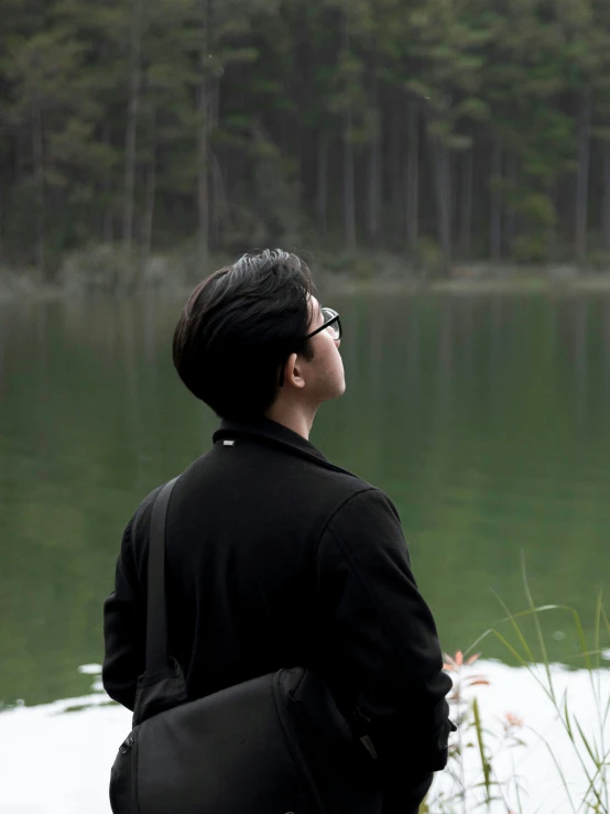 a woman in a black sweater stands by the water