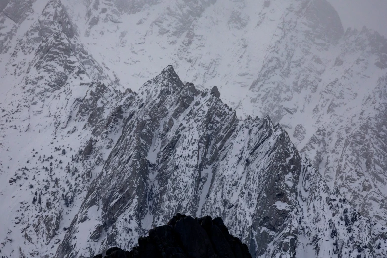 mountain range covered in snow and snow falling off the top