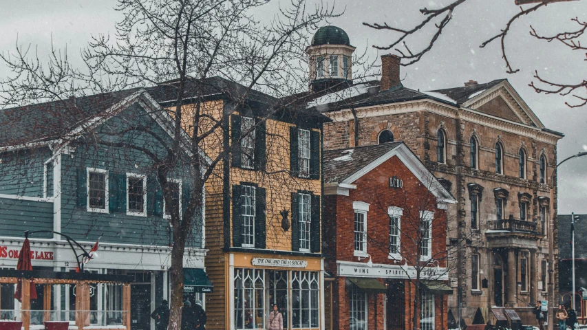 the corner building in front of this old shopping district has snow falling on it