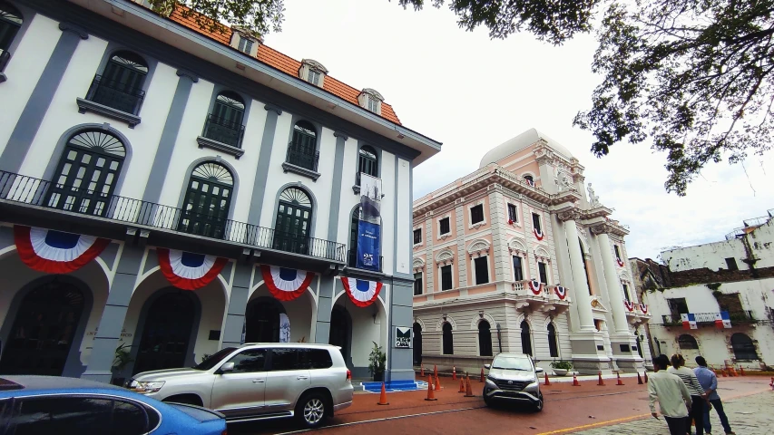 two old buildings in a row of cars parked in the street