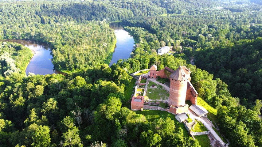 a castle surrounded by lush green trees and a river in the distance