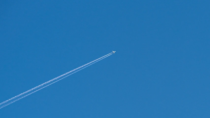airplane flying upward in a blue sky above