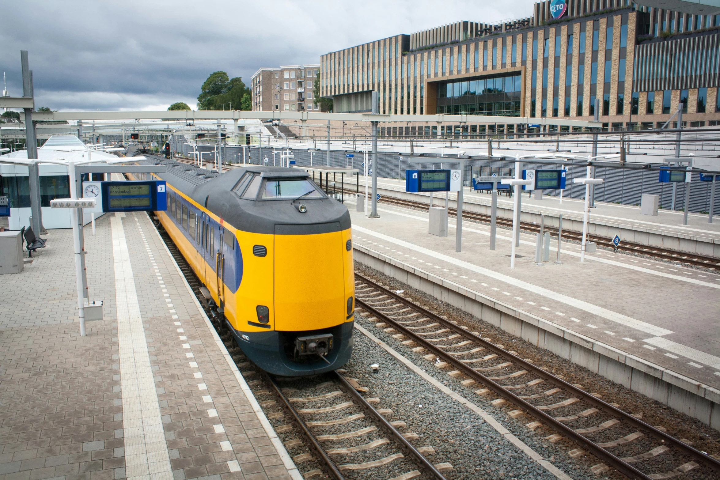 yellow and gray train on the tracks next to the building