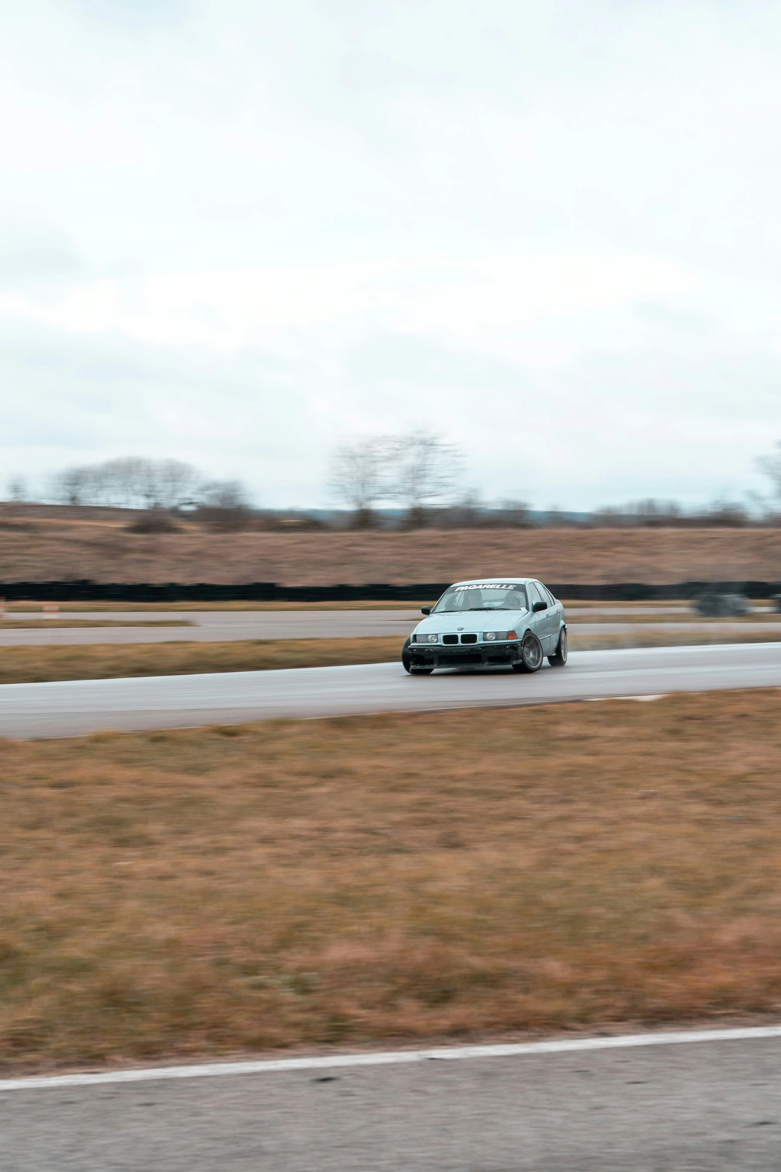 a bmw race car on a track next to grass