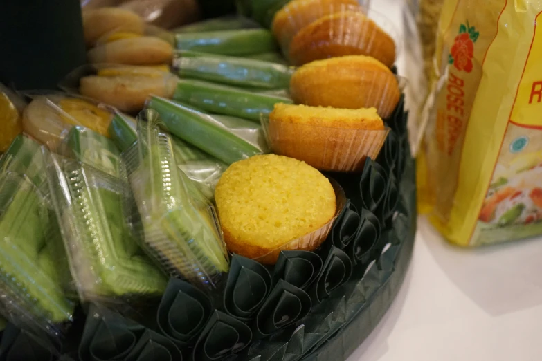 corn cupcakes and some green beans are being held by plastic wrappers