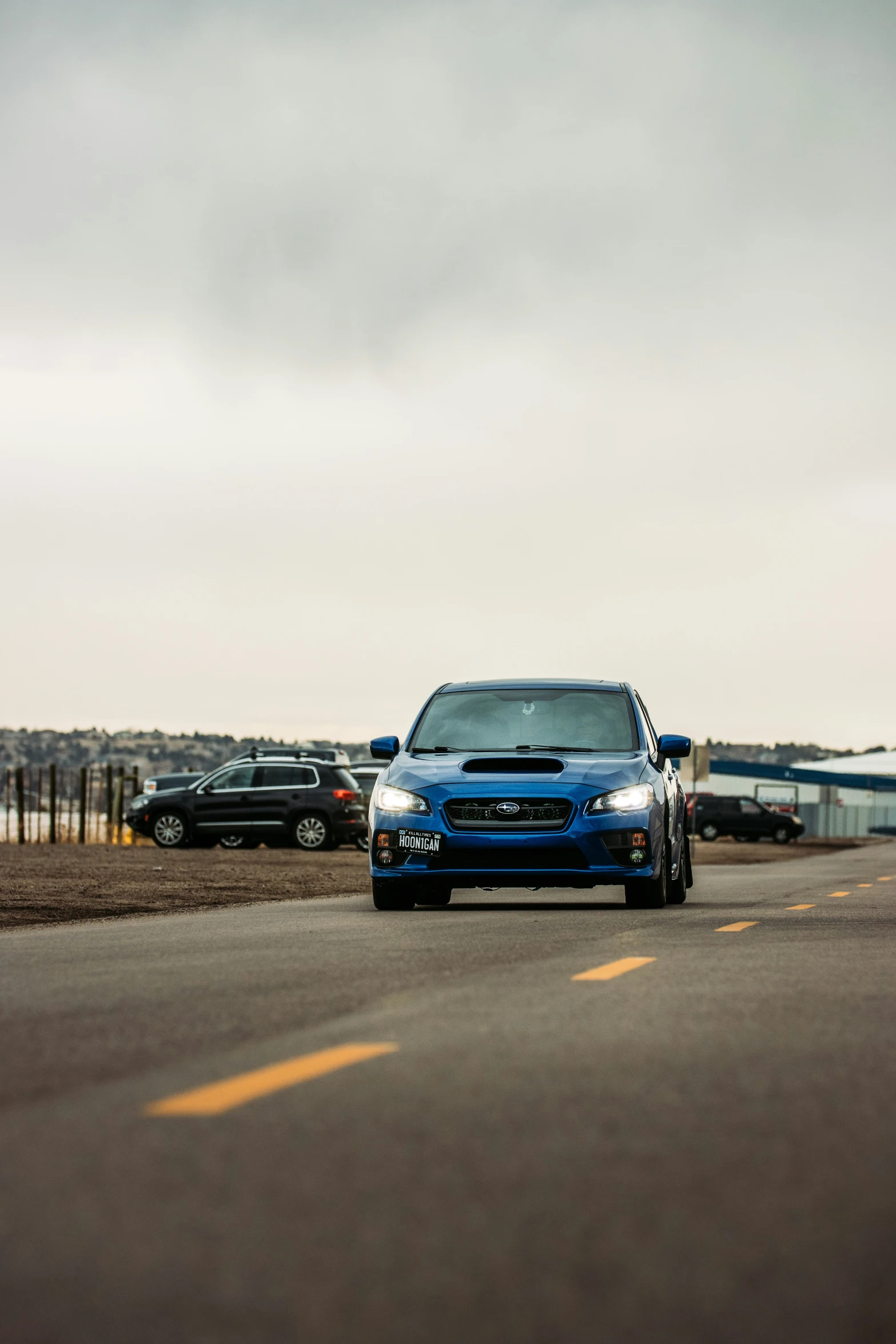 a blue subarunt driving down a highway with others in the background