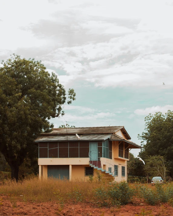 an empty house with three windows surrounded by tall grass