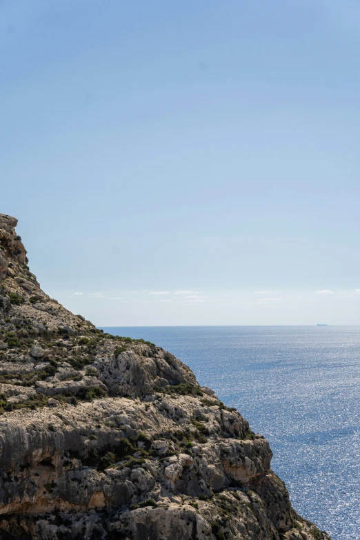 a small hill with blue water under a bright sky