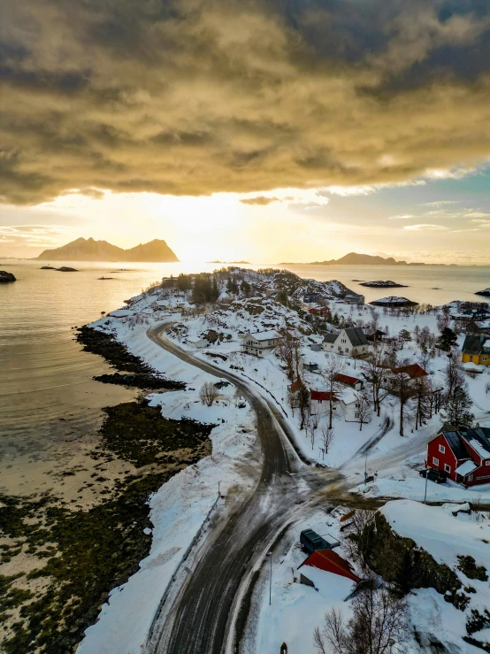 a road winds through the snow in front of a coastline