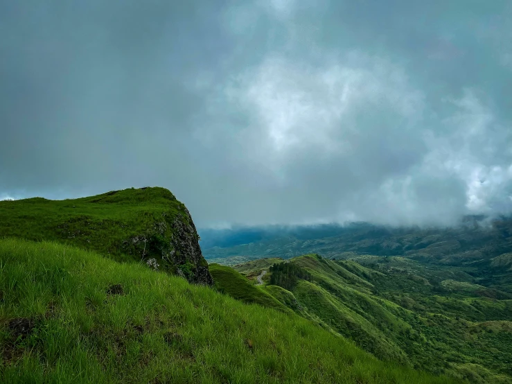 a tall green hill on top of a lush green field