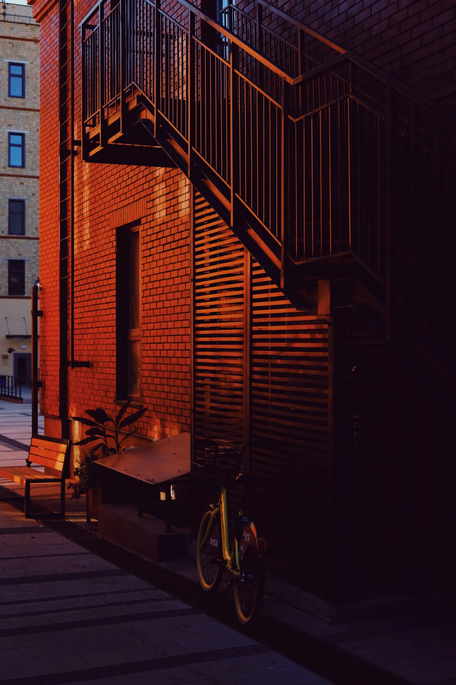 a yellow bicycle sits beside the stairs to a building