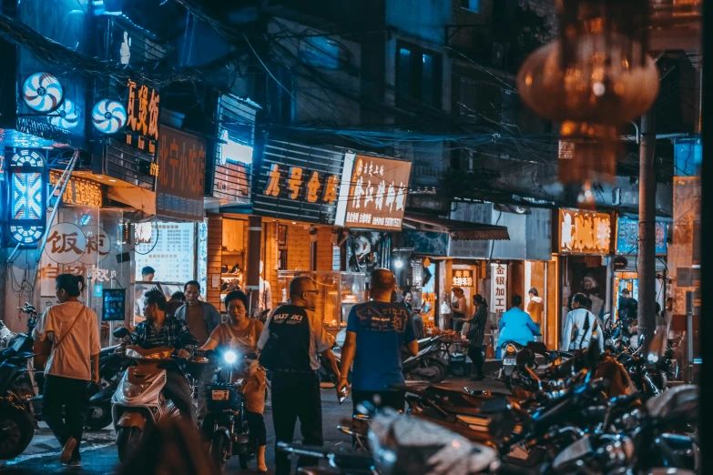 many motorcycles and people on a city street at night