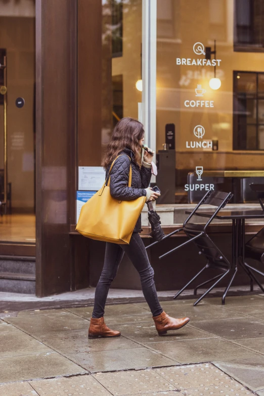 a woman walking with a large yellow handbag