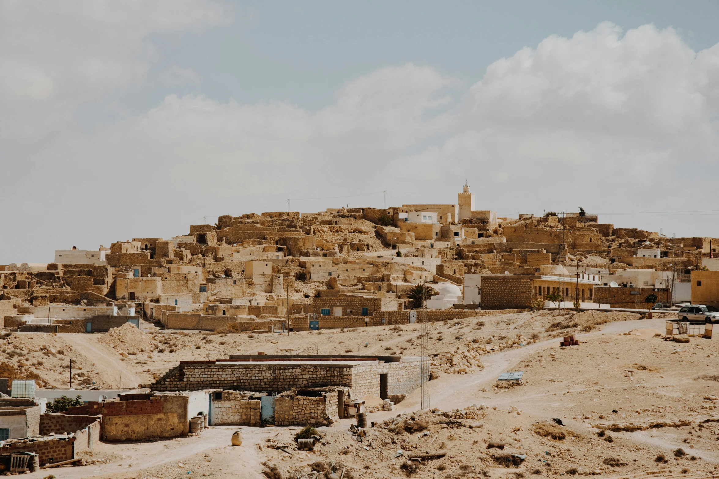 an old town with large roofs and brown dirt hillside