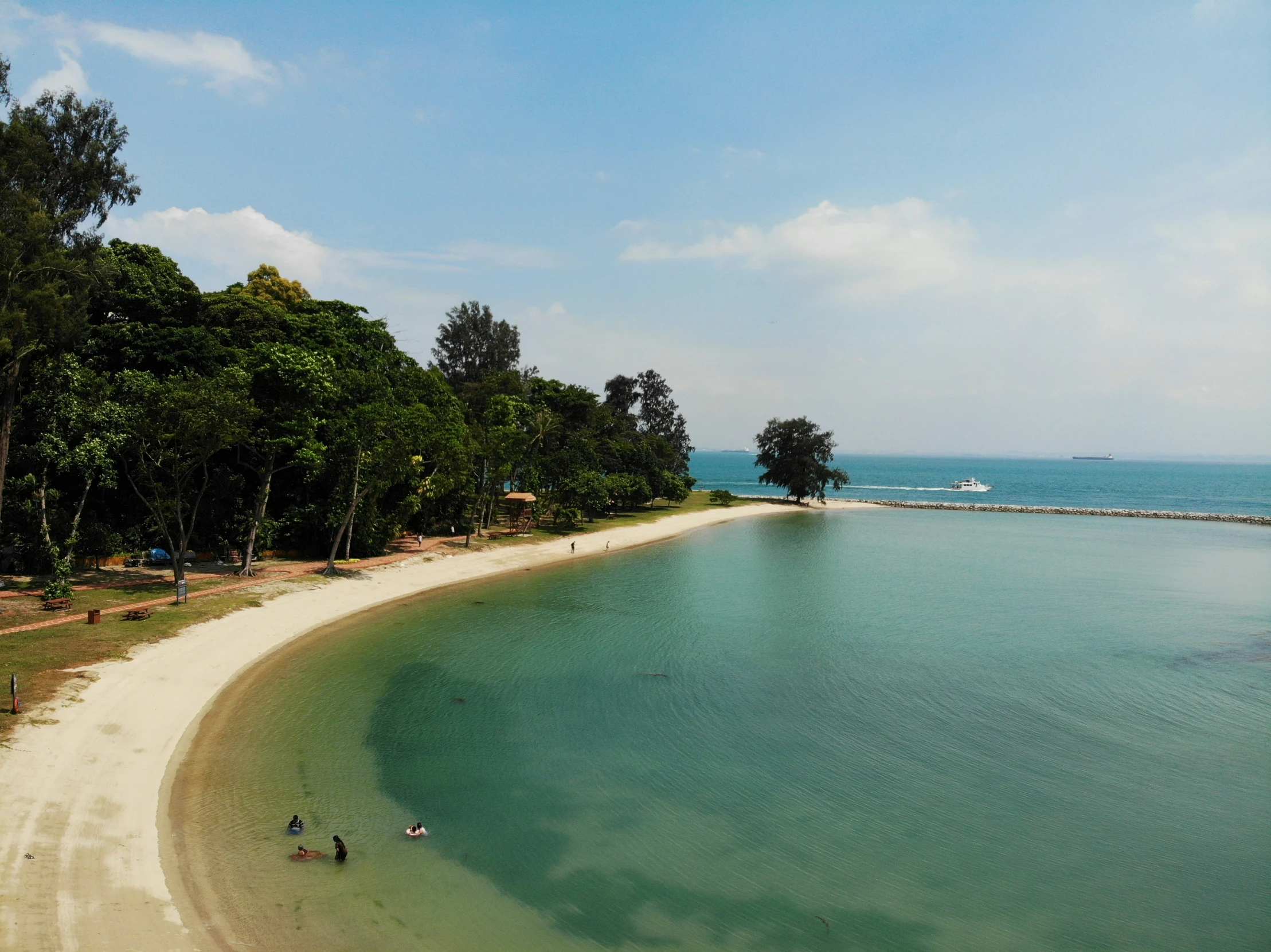 people walking and sitting at a sandy beach area