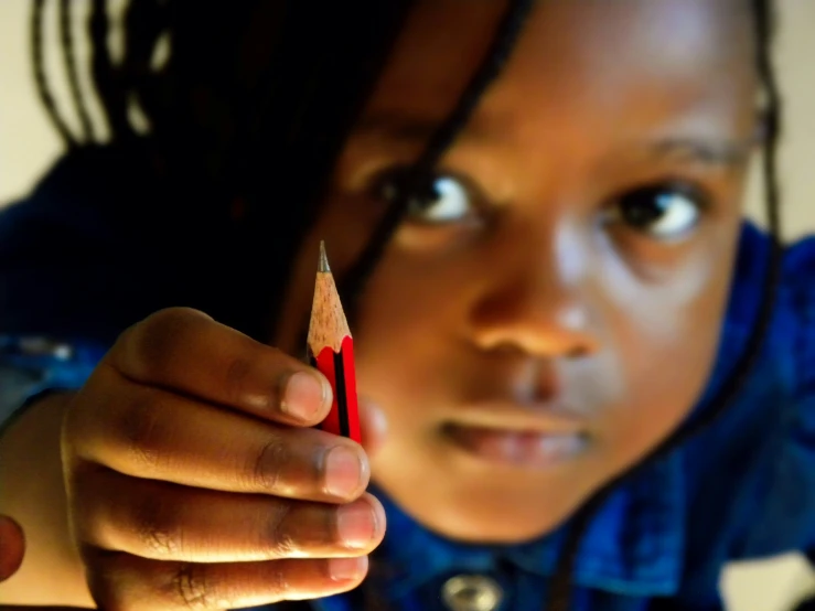 a young person holding a red pencil and pointing it in the direction