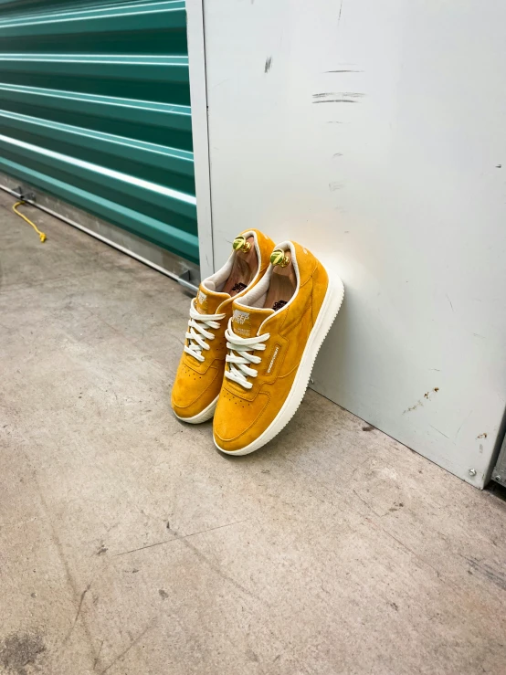 yellow shoes are sitting on the sidewalk against a green wall