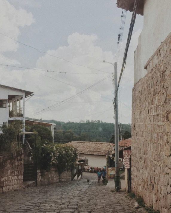 people walk down the street from houses with cobblestone walkways