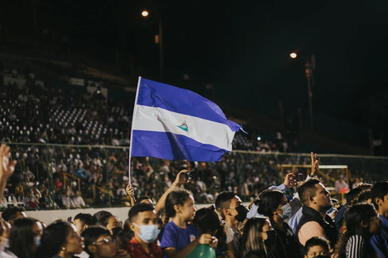 a group of people at a stadium with a flag flying