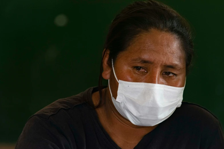 a woman wearing a white face mask on a dark background