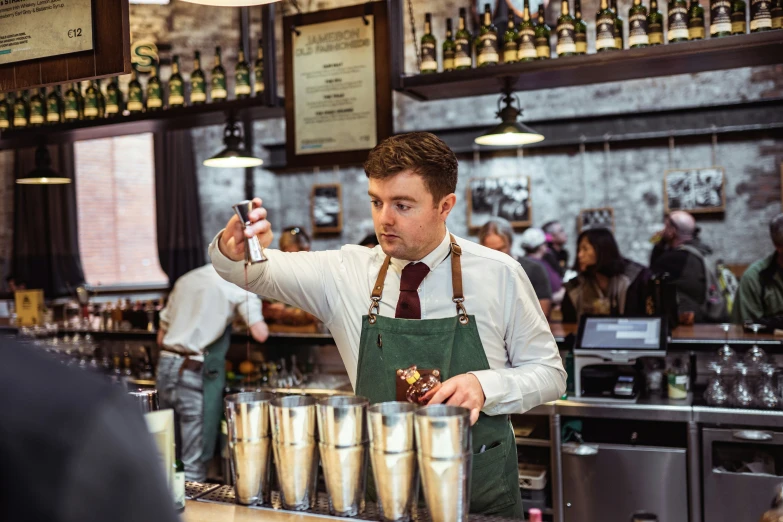 a man in white shirt and tie pouring beverages