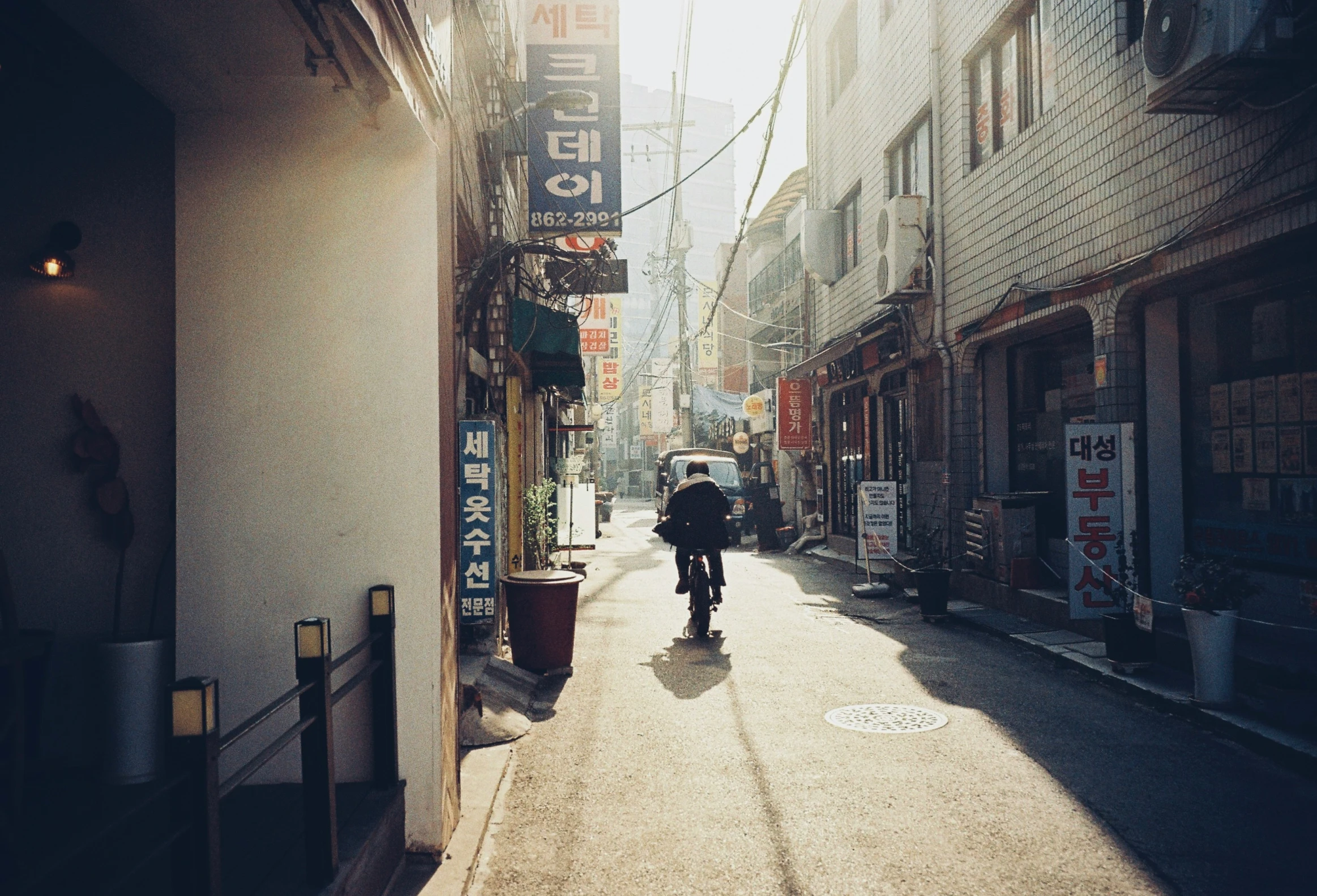 an alley with the sun shining through the buildings