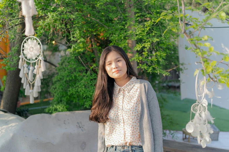 a girl posing for a picture while standing under a tree