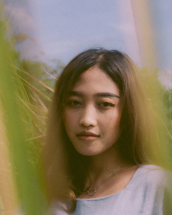 an asian woman poses while behind a tall palm tree