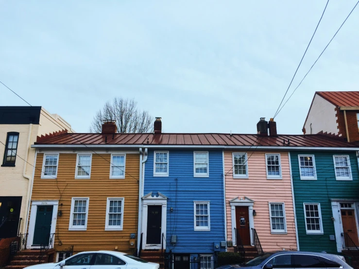 some cars parked along side of houses with many different colored painted them