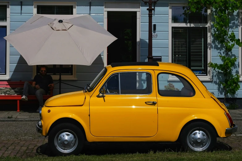 an old fashioned car with a white umbrella leaning against a house