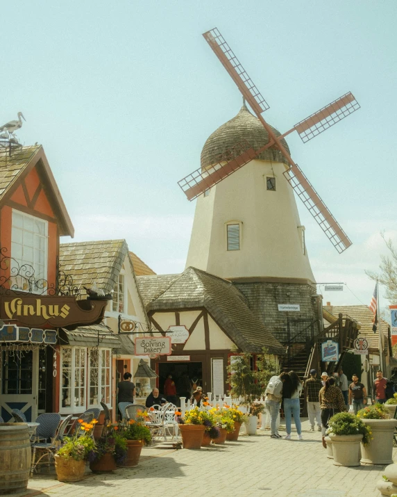 people are walking by an old windmill