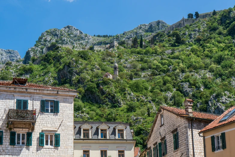 a street filled with stone buildings in front of a green mountain