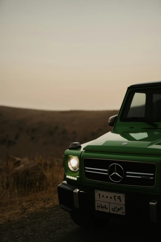 a green mercedes benz truck parked near some grass