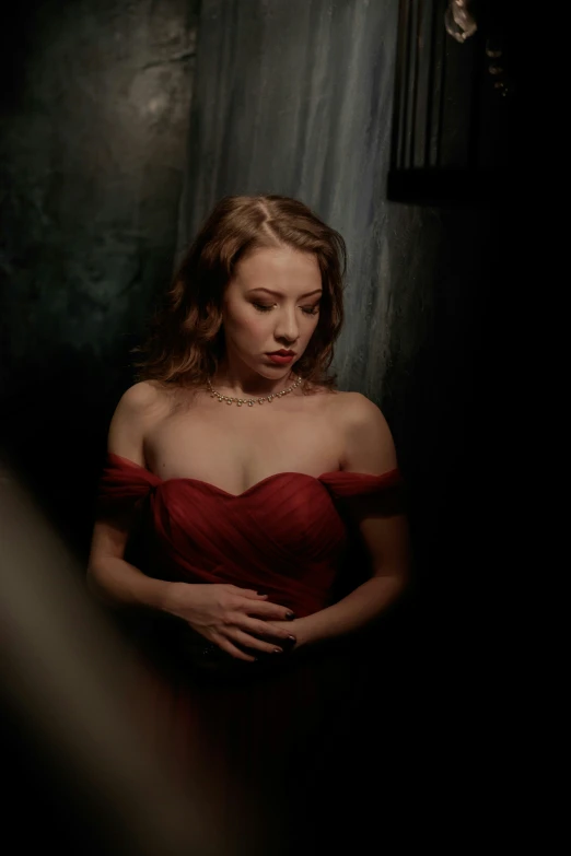 a woman standing in a room while wearing a red dress