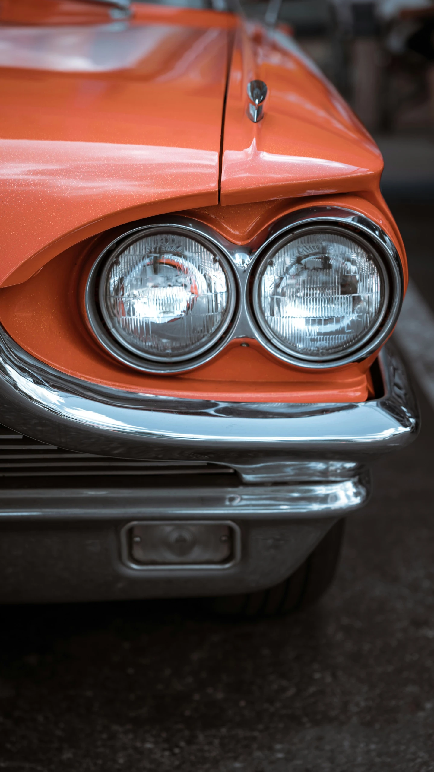 an orange car with the head lights on is shown