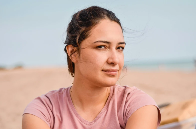 a girl is sitting in front of the beach with a boat