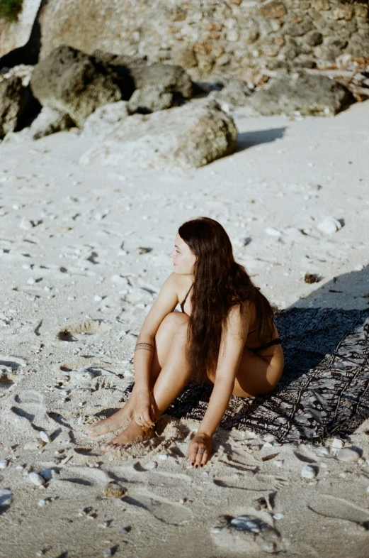  woman in black bikini laying on the sand