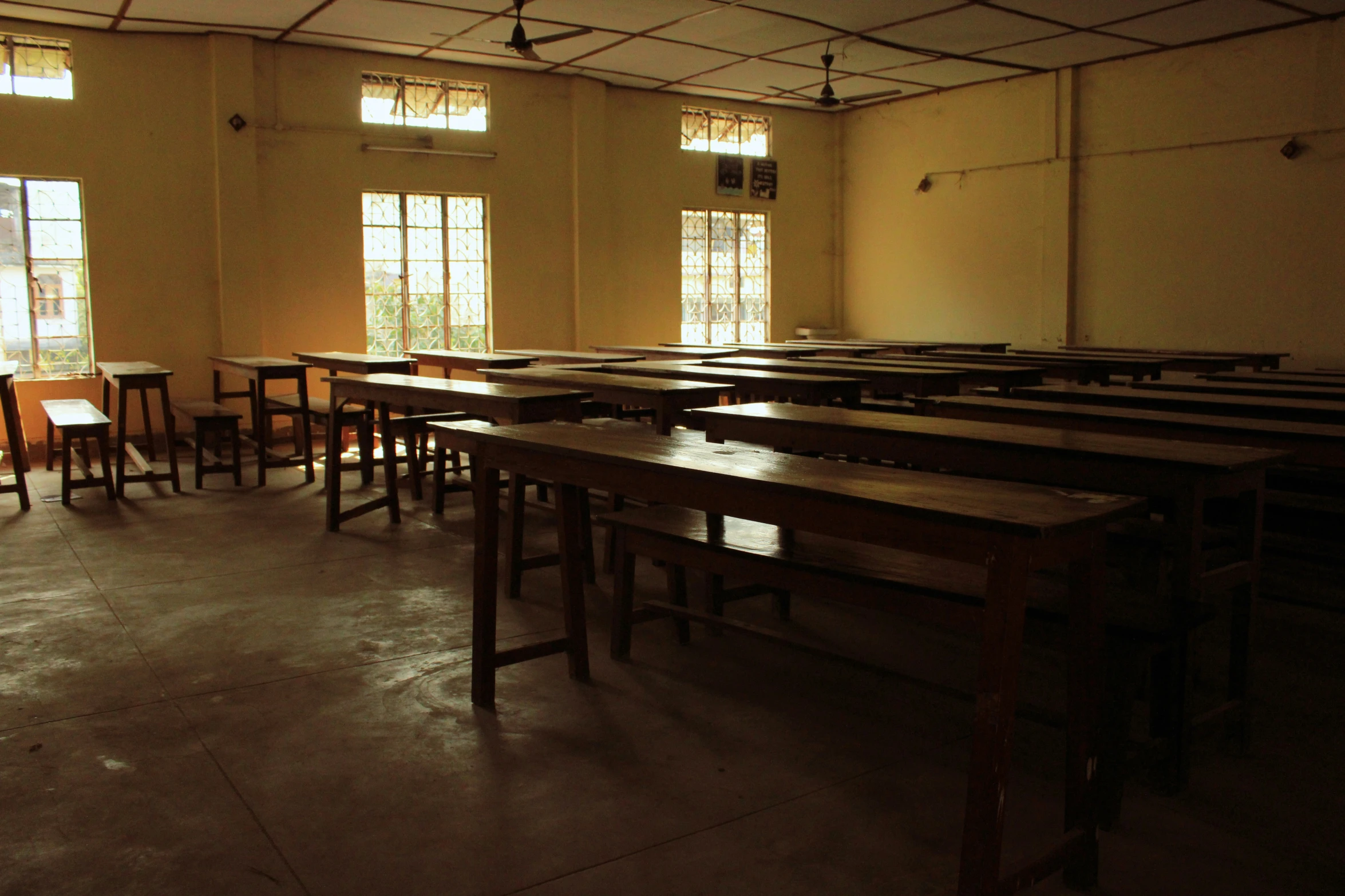 rows of empty desks line the walls and floor in a room that has large windows