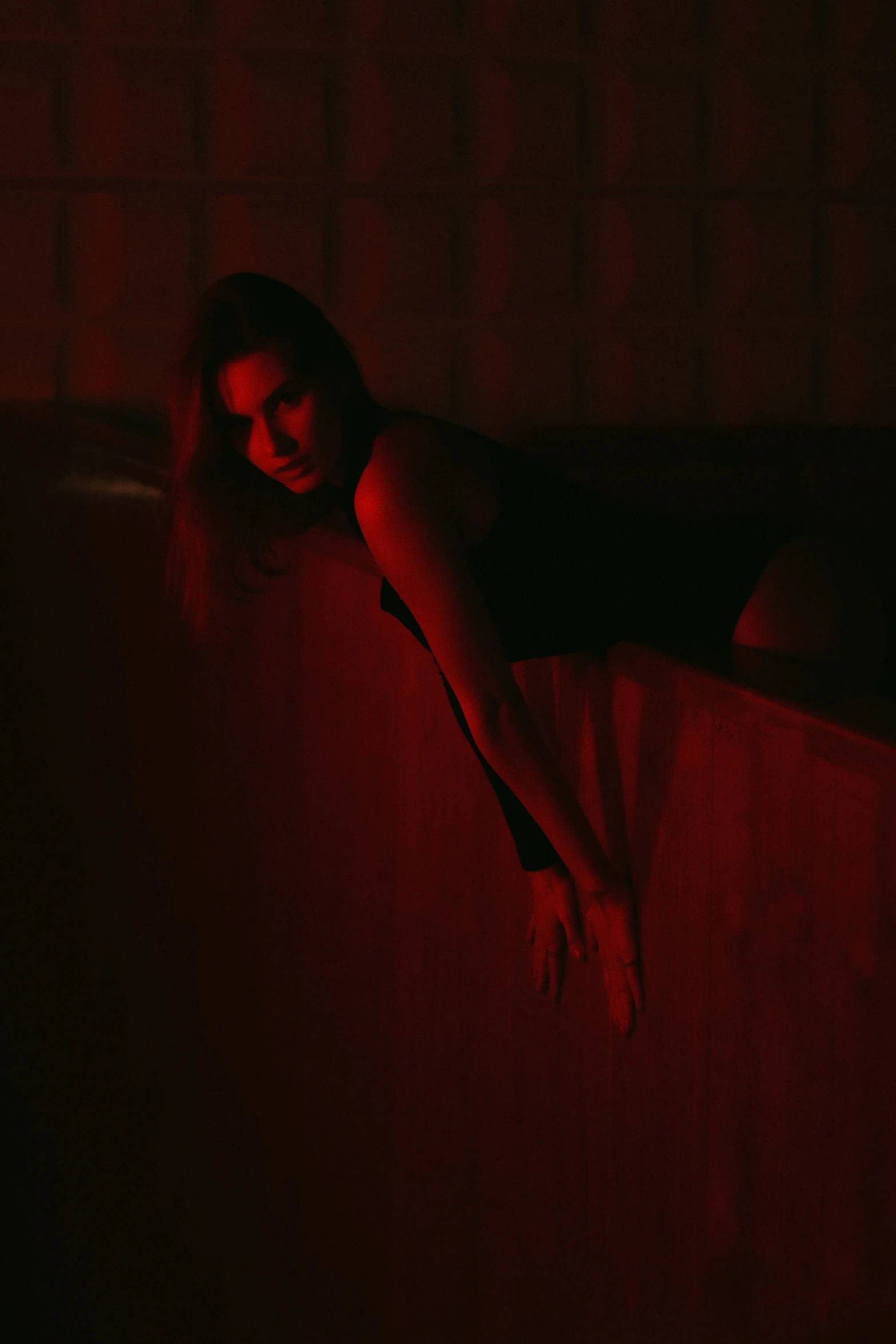 a woman laying down in the dark near a window