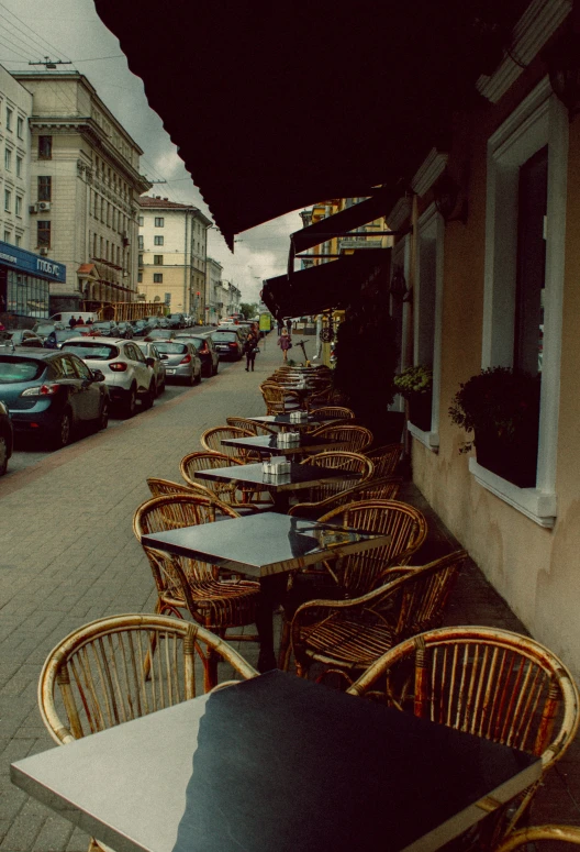 a row of tables and chairs along a building's sidewalk