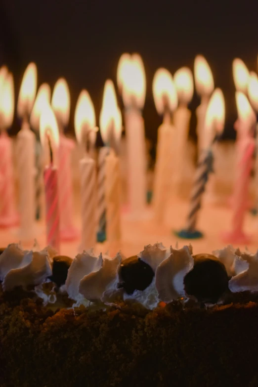 many candles glow brightly behind a birthday cake
