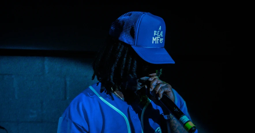 a male in a blue baseball cap holding a microphone