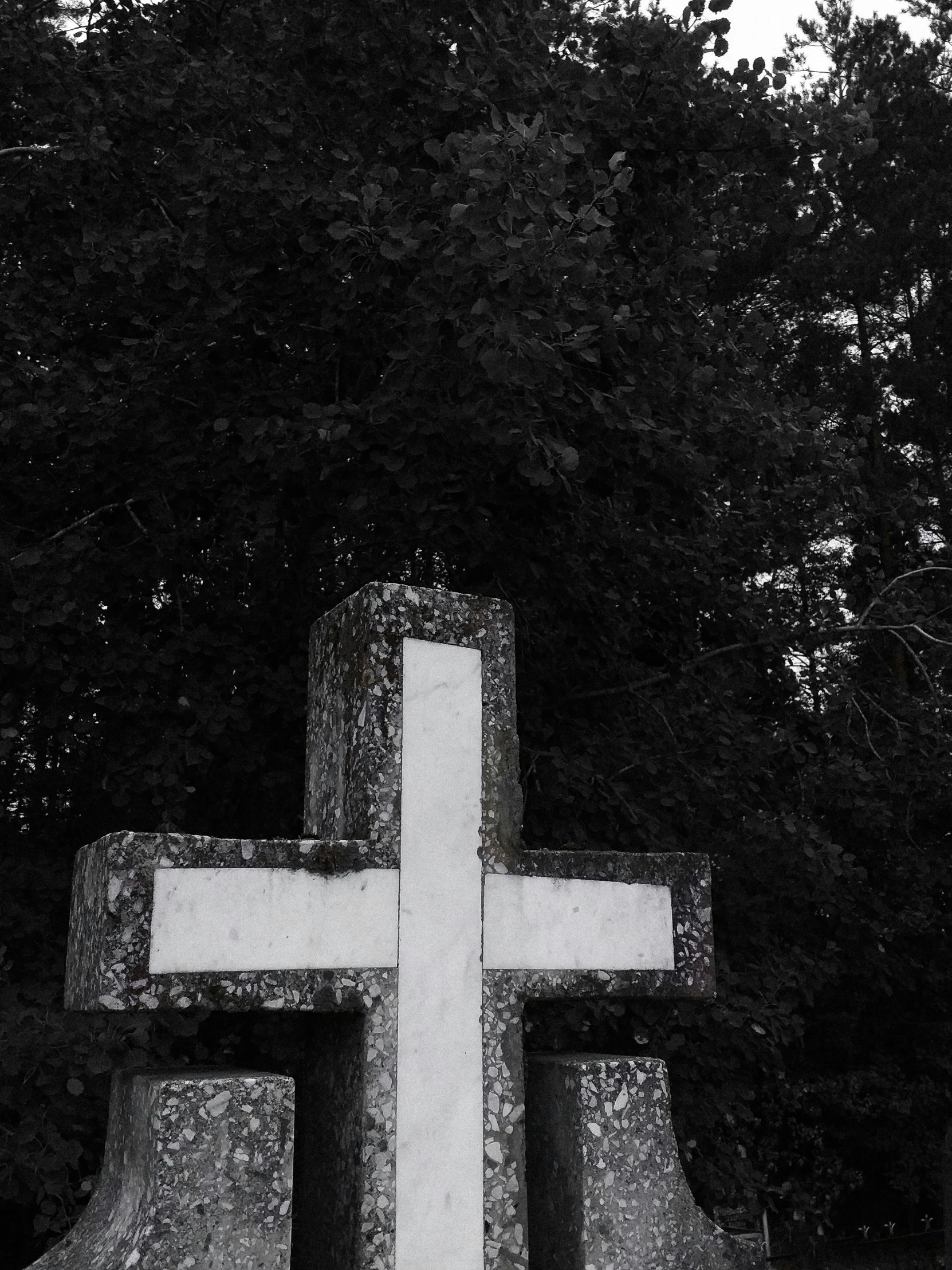 a cross made out of rocks near trees